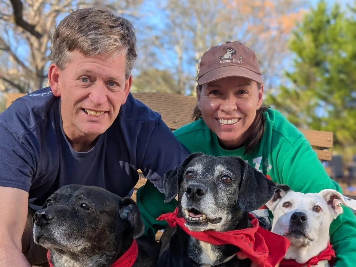 Barry and Lorraine smiling with their dogs Sammy, Dixie, and Lucky outdoors